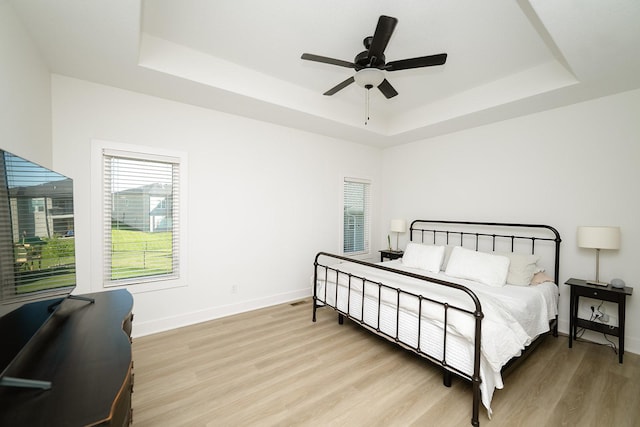16427 N Valley Dr, Urbandale, IA 50323 - bedroom with a tray ceiling, light wood-type flooring, and a ceiling fan