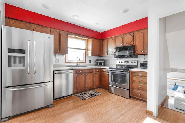 2106 62nd St, Des Moines, IA 50322 - kitchen with appliances with stainless steel finishes, a sink, light wood-style flooring, light countertops, and brown cabinets