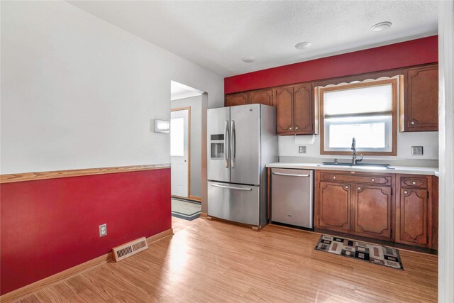 2106 62nd St, Des Moines, IA 50322 - kitchen with stainless steel appliances, a sink, light countertops, light wood finished floors, and baseboards