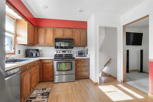 2106 62nd St, Des Moines, IA 50322 - kitchen featuring appliances with stainless steel finishes, a sink, light countertops, brown cabinetry, and light wood-type flooring
