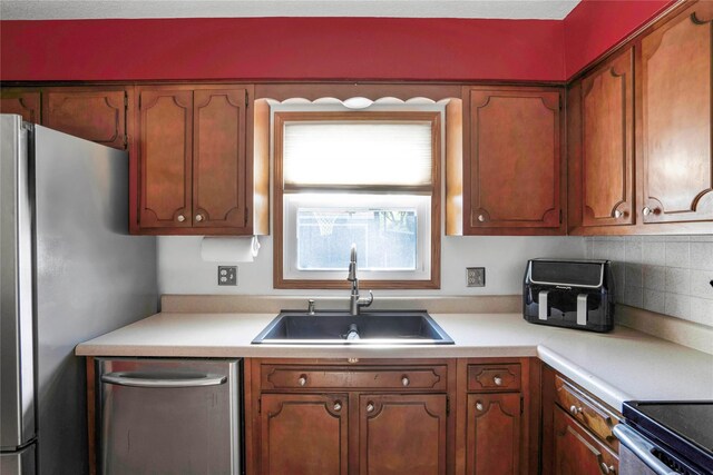 2106 62nd St, Des Moines, IA 50322 - kitchen with a sink, appliances with stainless steel finishes, light countertops, and brown cabinetry