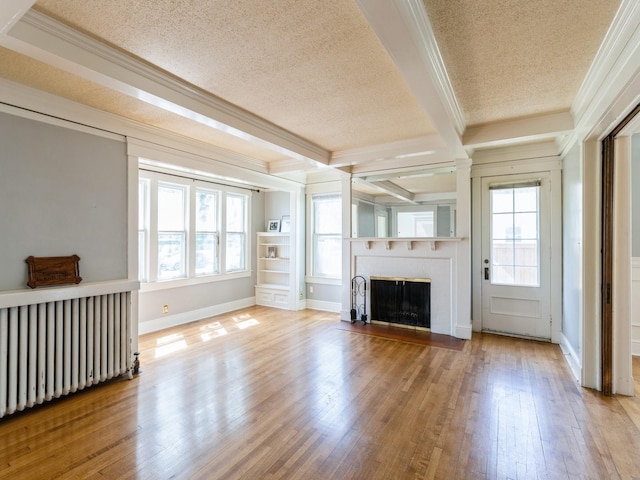 1070 37th St, Des Moines, IA 50311 - unfurnished living room with radiator, crown molding, a textured ceiling, healthy amount of natural light, and a fireplace with flush hearth