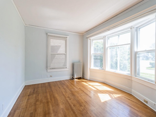 1070 37th St, Des Moines, IA 50311 - unfurnished room featuring radiator heating unit, wood finished floors, baseboards, and crown molding