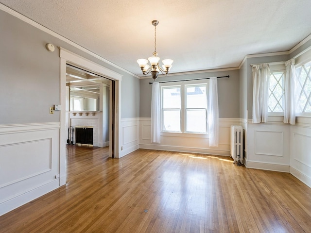1070 37th St, Des Moines, IA 50311 - unfurnished dining area with radiator heating unit, crown molding, a chandelier, wainscoting, and healthy amount of natural light