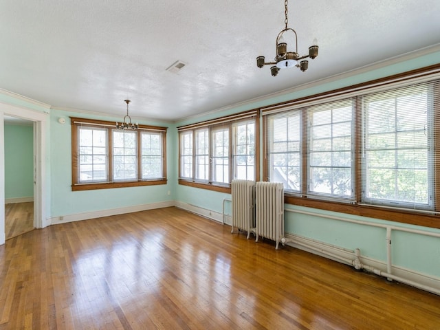 1070 37th St, Des Moines, IA 50311 - empty room with a chandelier, radiator, plenty of natural light, crown molding, and wood finished floors