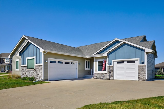 1412 NE Aspen Ct, Grimes, IA 50111 - view of front of home with board and batten siding, stone siding, an attached garage, and driveway