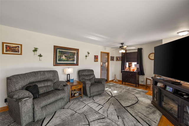 living area featuring wood finished floors, ceiling fan, and baseboards