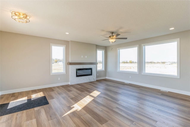 17151 Plum Dr, Urbandale, IA 50323 - unfurnished living room with baseboards, a glass covered fireplace, wood finished floors, and recessed lighting