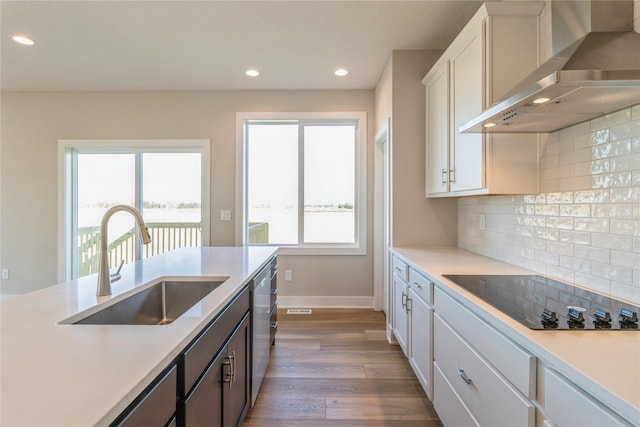 17151 Plum Dr, Urbandale, IA 50323 - kitchen with wall chimney range hood, a sink, black electric cooktop, light countertops, and dishwasher