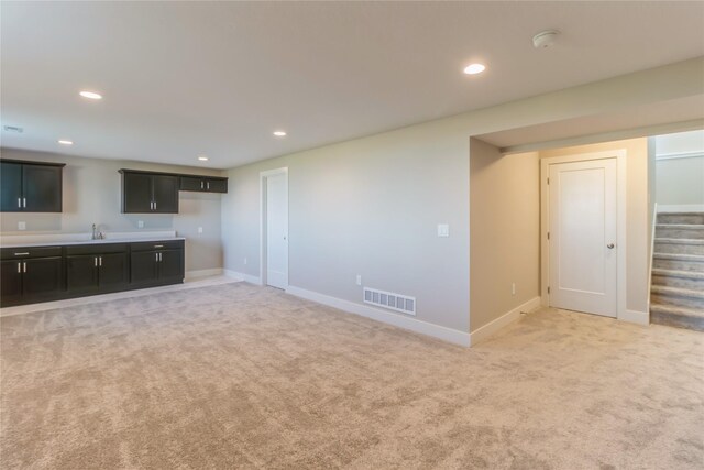 17151 Plum Dr, Urbandale, IA 50323 - unfurnished living room featuring light colored carpet, stairs, baseboards, recessed lighting, and bar area
