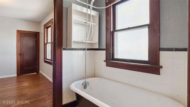 full bath with a freestanding tub, wood finished floors, and baseboards