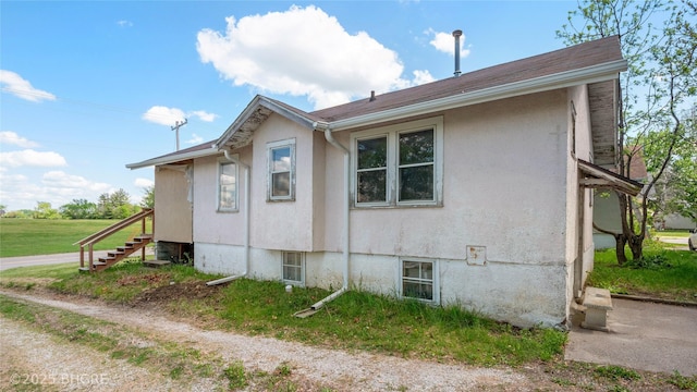 view of side of home with stairs and stucco siding