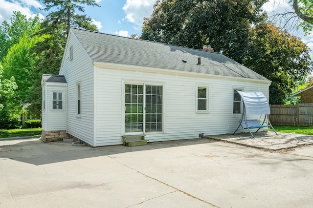 back of property featuring a patio, roof with shingles, and fence