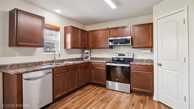 1508 E Euclid Ave, Indianola, IA 50125 - kitchen featuring stainless steel appliances, a sink, dark countertops, light wood-style floors, and recessed lighting