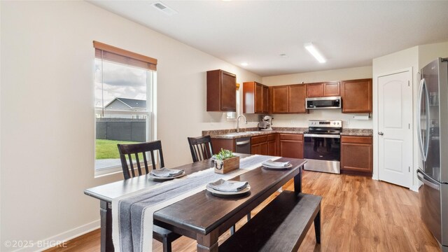 1508 E Euclid Ave, Indianola, IA 50125 - kitchen with stainless steel appliances, light wood-style floors, brown cabinets, a sink, and baseboards
