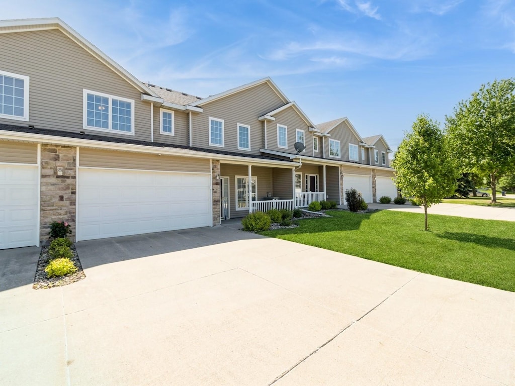 10615 Hickory Dr Unit 6, Urbandale, IA 50322 - view of property with a porch, a front yard, driveway, an attached garage, and stone siding