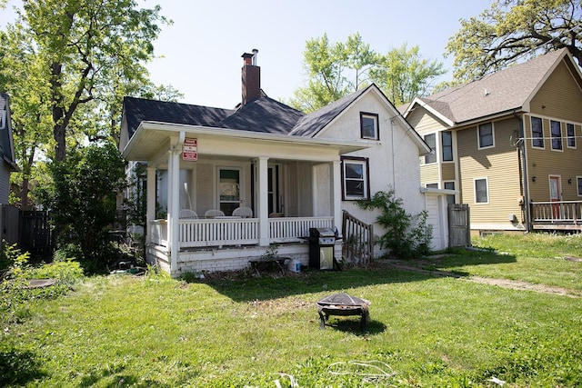 1143 27th St, Des Moines, IA 50311 - view of front of home with a porch, a fire pit, a front yard, a chimney, and stucco siding