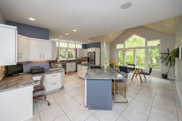 14943 Holcomb Ave, Clive, IA 50325 - kitchen featuring appliances with stainless steel finishes, a breakfast bar area, a kitchen island, light tile patterned flooring, and lofted ceiling