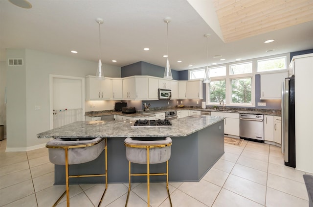14943 Holcomb Ave, Clive, IA 50325 - kitchen with stainless steel appliances, a kitchen island, light tile patterned floors, white cabinetry, and light stone countertops