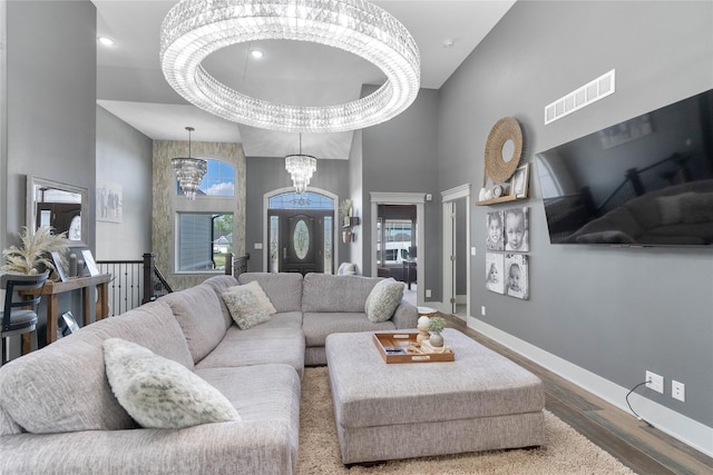 living area featuring wood finished floors, a chandelier, baseboards, and a high ceiling