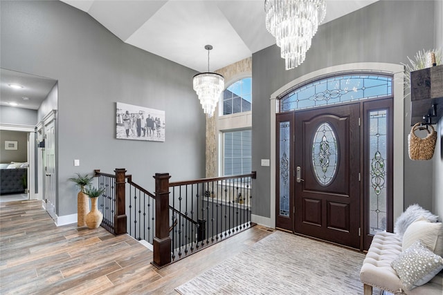foyer entrance featuring a chandelier, wood finished floors, a towering ceiling, and baseboards