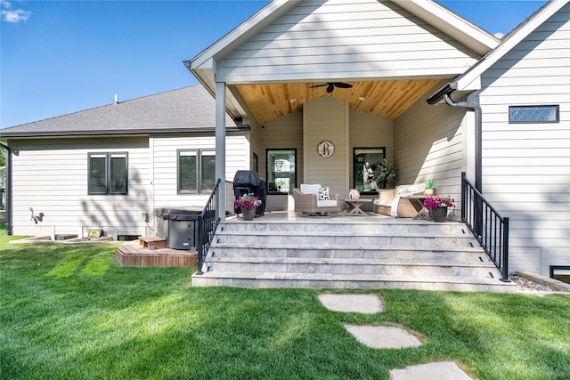 back of house featuring a hot tub, a yard, a shingled roof, and ceiling fan