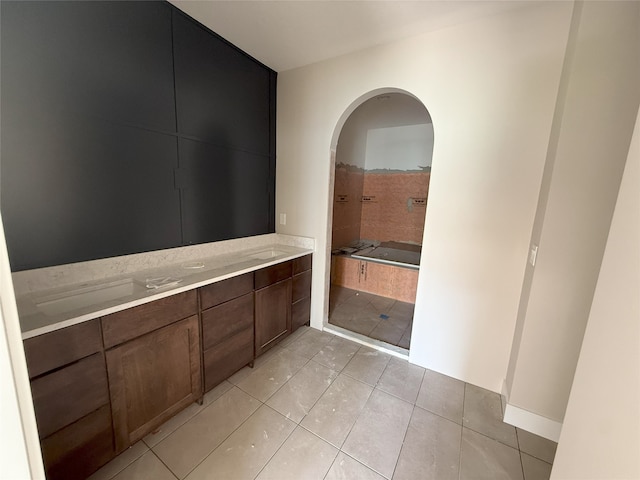 full bath featuring tile patterned floors, a tub to relax in, and double vanity