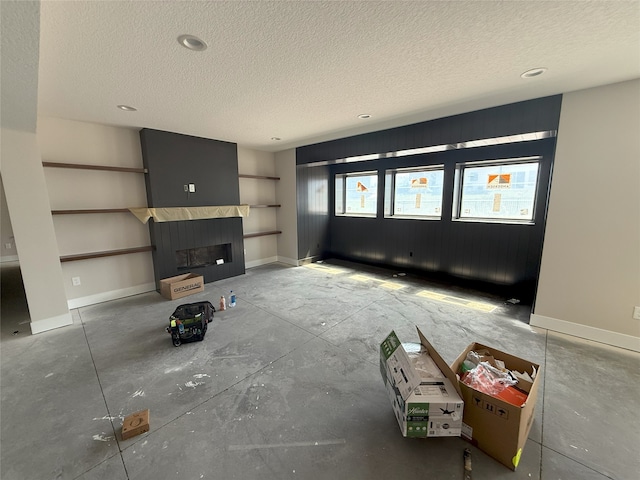 unfurnished living room with a textured ceiling, a fireplace, and baseboards