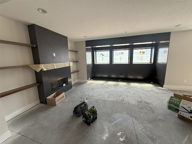 unfurnished living room featuring a textured ceiling, a fireplace, and baseboards