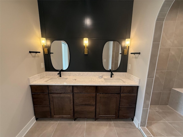 1128 NW 29th Ct, Grimes, IA 50111 - bathroom featuring tile patterned floors, double vanity, and baseboards