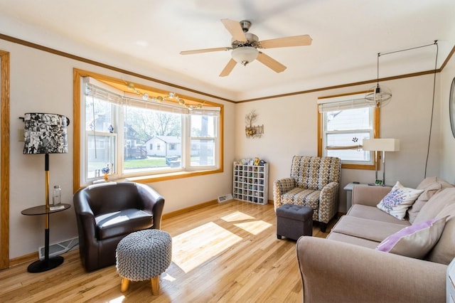 2322 E 39th St, Des Moines, IA 50317 - living room featuring plenty of natural light, light wood-type flooring, ornamental molding, and a ceiling fan