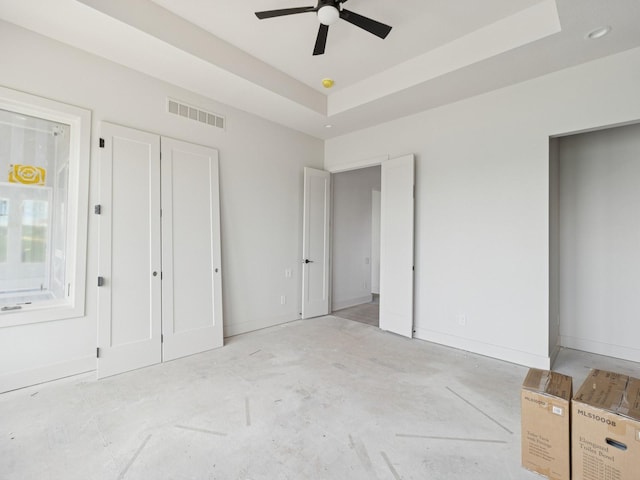 17406 Oakwood Dr, Urbandale, IA 50322 - unfurnished bedroom featuring a raised ceiling, unfinished concrete floors, baseboards, and ceiling fan