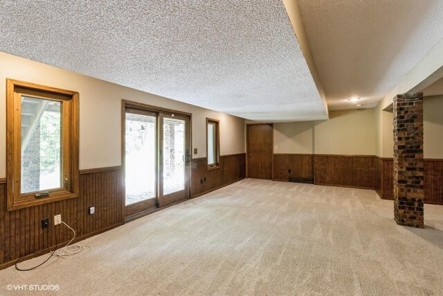 6406 Theresa Dr, Johnston, IA 50131 - unfurnished living room with a wainscoted wall, wood walls, a textured ceiling, plenty of natural light, and carpet