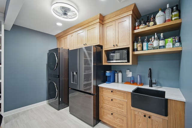 1919 Arlington Ave, Des Moines, IA 50314 - kitchen with built in microwave, stainless steel fridge, a sink, stacked washer and clothes dryer, and light countertops