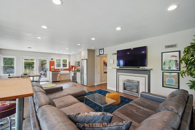 1919 Arlington Ave, Des Moines, IA 50314 - living room with light wood-style floors, recessed lighting, a tile fireplace, and baseboards