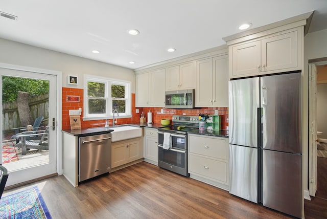 1919 Arlington Ave, Des Moines, IA 50314 - kitchen featuring appliances with stainless steel finishes, a sink, dark countertops, dark wood finished floors, and decorative backsplash