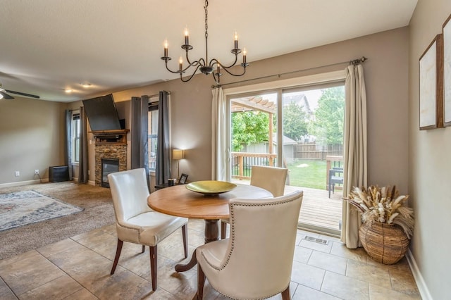 dining space with a chandelier, baseboards, a fireplace, and a ceiling fan