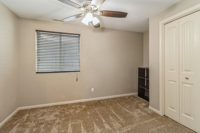 unfurnished bedroom with carpet flooring, a closet, baseboards, and a ceiling fan