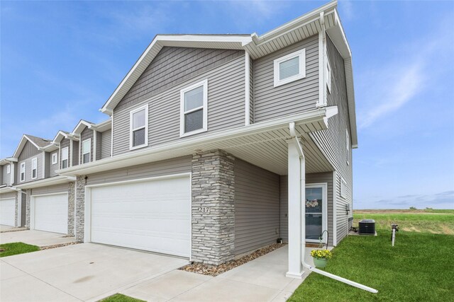 217 NE Glendale Ln, Ankeny, IA 50021 - view of property with an attached garage, central AC unit, stone siding, a front lawn, and driveway