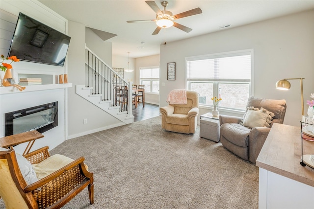 217 NE Glendale Ln, Ankeny, IA 50021 - carpeted living room featuring a glass covered fireplace, stairway, ceiling fan, and baseboards