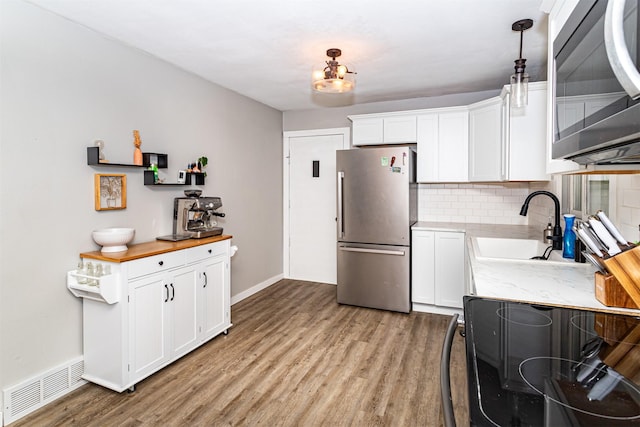 4014 Aplin Rd, Ames, IA 50014 - kitchen featuring appliances with stainless steel finishes, a sink, light wood-type flooring, tasteful backsplash, and white cabinets