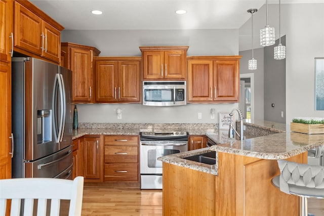 913 SE Trail Ridge Rd, Grimes, IA 50111 - kitchen featuring stainless steel appliances, a peninsula, a breakfast bar area, light stone counters, and light wood-type flooring