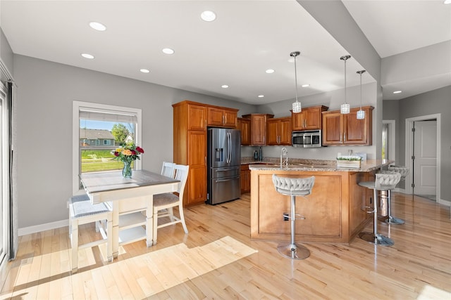 913 SE Trail Ridge Rd, Grimes, IA 50111 - kitchen featuring appliances with stainless steel finishes, recessed lighting, light stone countertops, brown cabinets, and a breakfast bar area