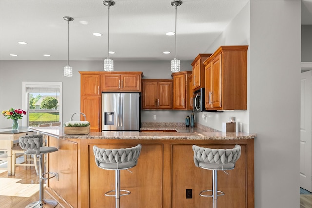 913 SE Trail Ridge Rd, Grimes, IA 50111 - kitchen with stainless steel appliances, brown cabinetry, light stone countertops, a peninsula, and recessed lighting