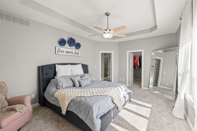 913 SE Trail Ridge Rd, Grimes, IA 50111 - bedroom featuring a tray ceiling, light carpet, a walk in closet, a closet, and baseboards