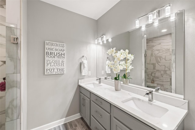 913 SE Trail Ridge Rd, Grimes, IA 50111 - full bath featuring double vanity, a marble finish shower, baseboards, and wood finished floors