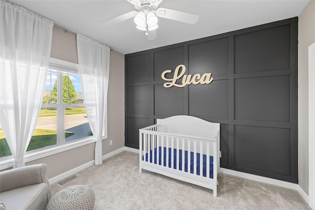 913 SE Trail Ridge Rd, Grimes, IA 50111 - bedroom featuring light carpet, a decorative wall, a crib, baseboards, and ceiling fan