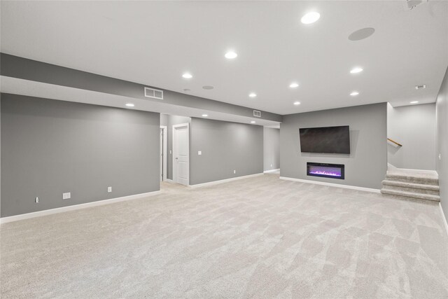 913 SE Trail Ridge Rd, Grimes, IA 50111 - finished below grade area with light colored carpet, recessed lighting, stairs, a glass covered fireplace, and baseboards