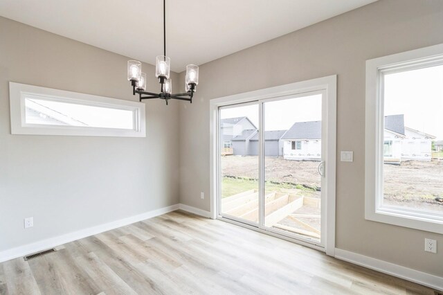 14512 Northpark Dr, Urbandale, IA 50111 - unfurnished dining area with a chandelier, healthy amount of natural light, wood finished floors, and baseboards