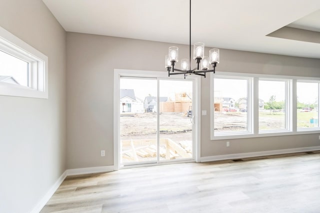 14512 Northpark Dr, Urbandale, IA 50111 - unfurnished dining area featuring a chandelier, healthy amount of natural light, wood finished floors, and baseboards